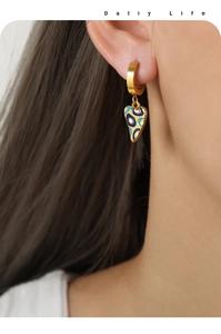 Detailaufnahme eines herzförmigen Evil Eye Anhängers am Ohr eines Models getragen