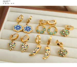 Detailansicht goldener Creolen mit Herz- und Blumenanhängern und blauem Emaille-Auge