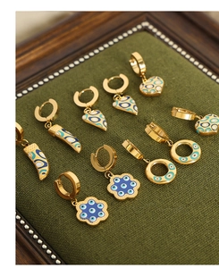 Detail von goldenen Evil-Eye-Ohrringen mit Emaille-Anhängern in Herz- und Blumenform
