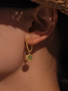 Detail of green agate earring with gold twist texture and a summer shadow aesthetic