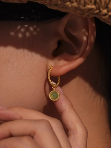 Detail of twisted gold earrings with green agate stone shown on a model