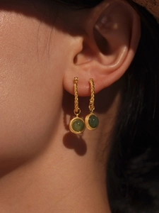Detail of twisted gold earrings featuring round green agate stone worn on model