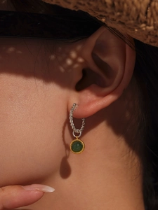 Detail of green agate twist earrings worn by model under natural sunlight shadows