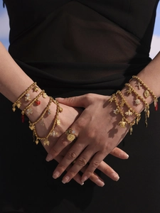 Detail of golden charm bracelet with star and turtle pendants on black fabric