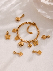 Detailed view of DIY stainless steel charm bracelet with sun and clover pendants in gold