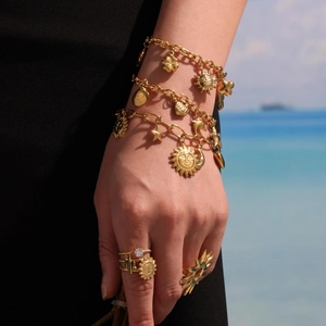 Gold-plated stainless steel charm bracelet with sun and starfish pendants on a model