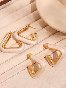 Detail of geometric gold-plated earrings with pearl resin inlay on velvet tray