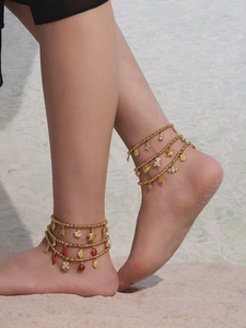 Close-up of gold beaded anklet featuring marine pendants and colorful enamel charms