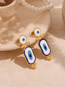 Détail de boucles d'oreilles œil porte-bonheur en émail bleu sur une coupelle en céramique