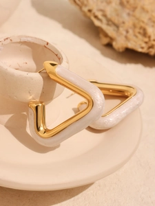 Detailed close-up of geometric triangle earrings with pearlescent resin and gold frames