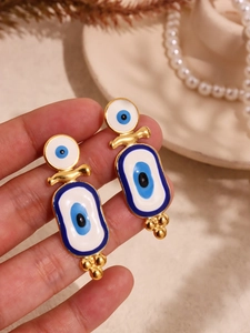 Vue détaillée des boucles d'oreilles Evil Eye dorées avec charmes émaillés et perles