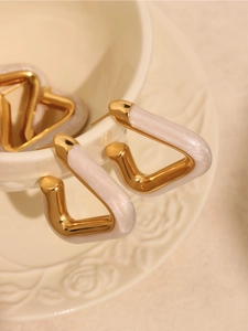 Macro shot of triangle drop earrings with gold metal and pearly white shimmer finish