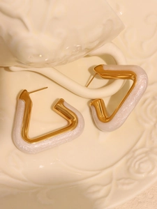 Detail of geometric triangle earrings with gold plating and sparkling white glitter resin