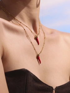 Detail of layered gold beaded chains featuring vibrant red chili pepper pendants for women