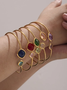 Macro view of multi-colored faceted crystal open bangles with gold plated bands on wrist
