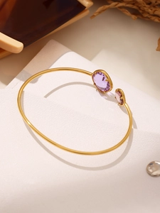 Close-up of gold plated stainless steel open bangle with purple oval crystals