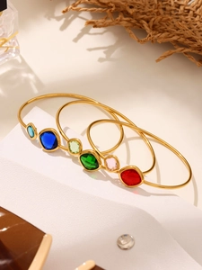 Detailed shot of gold-plated open bracelets with colorful Czech glass stones on white blocks