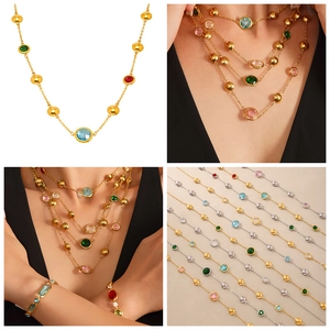 Close-up of golden necklace with colorful square glass stones and hollow circle links