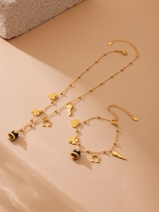 Detail of gold-plated stainless steel jewelry set featuring black enamel charms and charms
