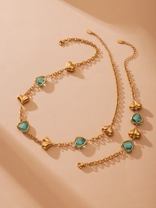 Detalle macro de conjunto de joyas en acero dorado con cristales azules de corazón