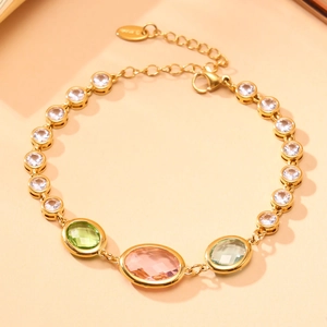 Détail d'une chaîne de cheville dorée avec pierres en verre tchèque vert et rose et fermoir