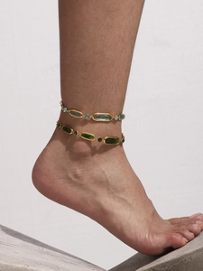 Detail of gold layered anklet set featuring light blue and emerald green crystals