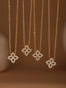 Detailansicht von vier goldenen Kleeblatt-Halsketten mit glitzernden Zirkonia-Kristallen