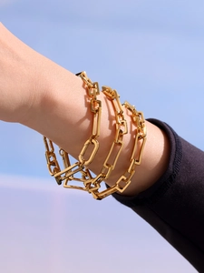 Nahaufnahme eines polierten vergoldeten Edelstahl Gliederketten Armbands am Handgelenk