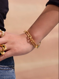 Detailansicht eines 18k vergoldeten Gliederkettenarmbands und Ringe am Handgelenk