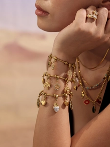 Detalle de pulseras de oro de 18k con dijes del árbol de la vida y circonitas en modelo