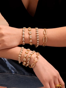 Close-up of stacked 18K gold plated bracelets with cubic zirconia and geometric links