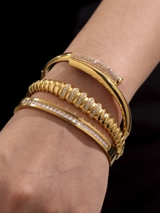 Close-up of golden bangle set featuring nail-shaped design and cubic zirconia pave detail