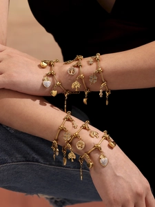 Detalle de set de pulseras de cadena de serpiente en oro 18k con árbol de vida y trébol