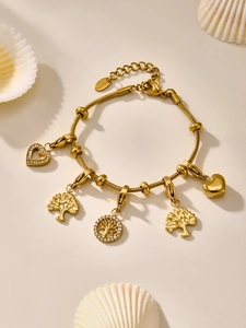 Detalle de pulsera de cadena de serpiente dorada con dijes de árbol de la vida y corazones en concha