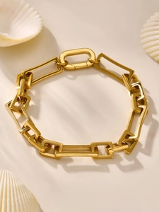 Nahaufnahme eines goldenen Gliederkettenarmbands mit Karabinerverschluss auf Muschel