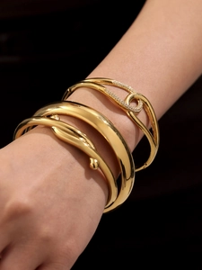 Detailed view of layered 18k gold plated bangles with zircon pave and twisted knot design