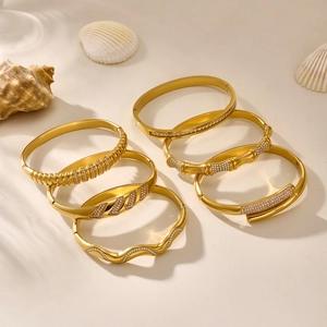 6-piece gold stainless steel bracelet set with zircon stones on beach sand background