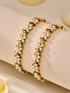 Detailed view of two gold-plated flower bracelets with clear zircons on a display stand