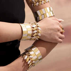 Bracciale a foglia bicolore e rigido largo testurizzato oro e bianco sul braccio donna