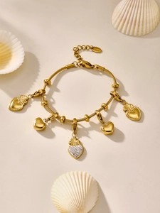 Detalle de pulsera de cadena de serpiente dorada con colgantes de corazón y circonitas