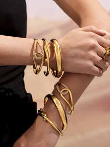 Stacked gold bracelets and ring set featuring minimalist crossover design and pave diamonds