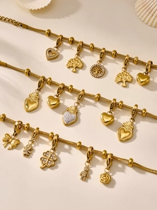 Vista detallada de cadenas doradas con dijes de trébol, corazón y oso con circonia