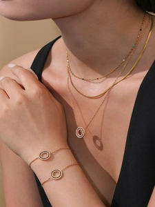 Detalle de collares y pulseras de capas bañadas en oro de 18k con dobles anillos de circón