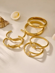 Close-up of gold irregular bangles with cubic zirconia and twisted cross details