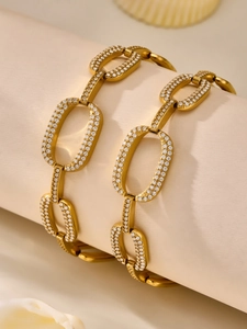 Close-up of gold chain bracelet featuring oval links with micro-pave white zircon stones