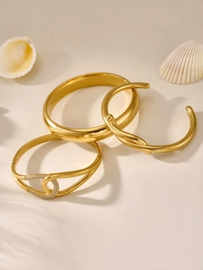 Detailed view of a 3-piece gold bangle set with pave zircon and twisted metal texture