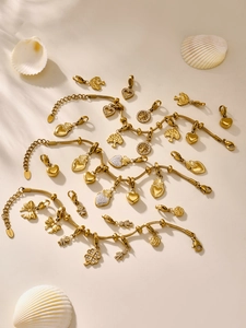 Detalle de colgantes de trébol en acero dorado y pulseras de oso sobre fondo beige