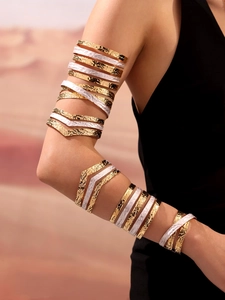 Dettaglio di bracciali da braccio sovrapposti placcati oro con texture martellata