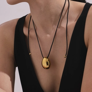Minimalist gold teardrop pendant necklace with black cord shown on model neck