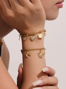 Detail van vergulde armbanden met fonkelende schildpad- en hartvormige hangertjes